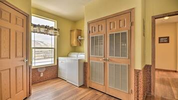 A laundry room with wooden doors, a washing machine, and a window with a view.