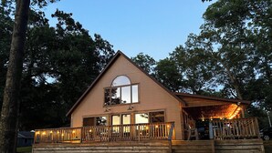 A two-story wooden cabin with a porch, large windows, and a circular skylight. - Peaceful Long Lake Cottage w/ Deck, Dock & Kayaks! (Branch)