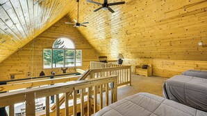 A cabin with a sloped ceiling, wooden walls, a balcony, and two beds. - Peaceful Long Lake Cottage w/ Deck, Dock & Kayaks! (Branch)