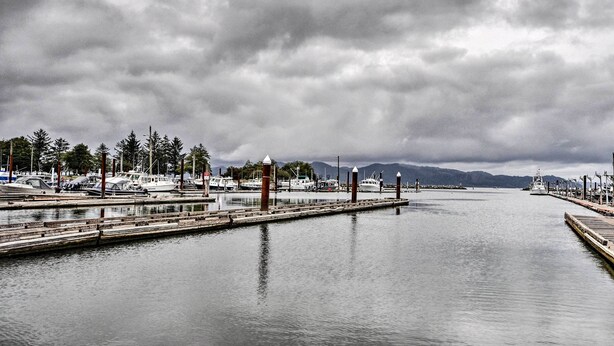 A marina with boats docked, a wooden pier, and a calm water body under a cloudy sky. - Hammond Home 2 Blocks to Marina & Columbia River! (Hammond)