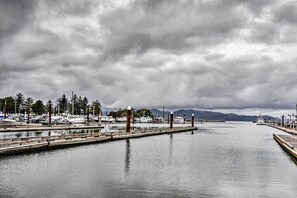 A marina with boats docked, a wooden pier, and a calm water body under a cloudy sky.