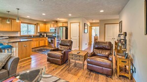 A spacious living area with leather chairs, a coffee table, and a kitchen in the background. - Hammond Home 2 Blocks to Marina & Columbia River! (Hammond)