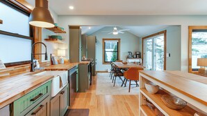 A modern kitchen with wooden countertops, a dining area with a table and chairs, and a large window providing natural light. - Winnipesaukee Lakefront Home With Dock & Views! (Alton Bay)