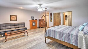 Ein Schlafzimmer mit einem Bett, einer hölzernen Bank, einem Sofa, einem Schminktisch und einem Deckenventilator.