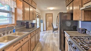 Eine Küche mit Holzschränken, einer Edelstahl-Spüle, einem Herd und einem Kühlschrank.