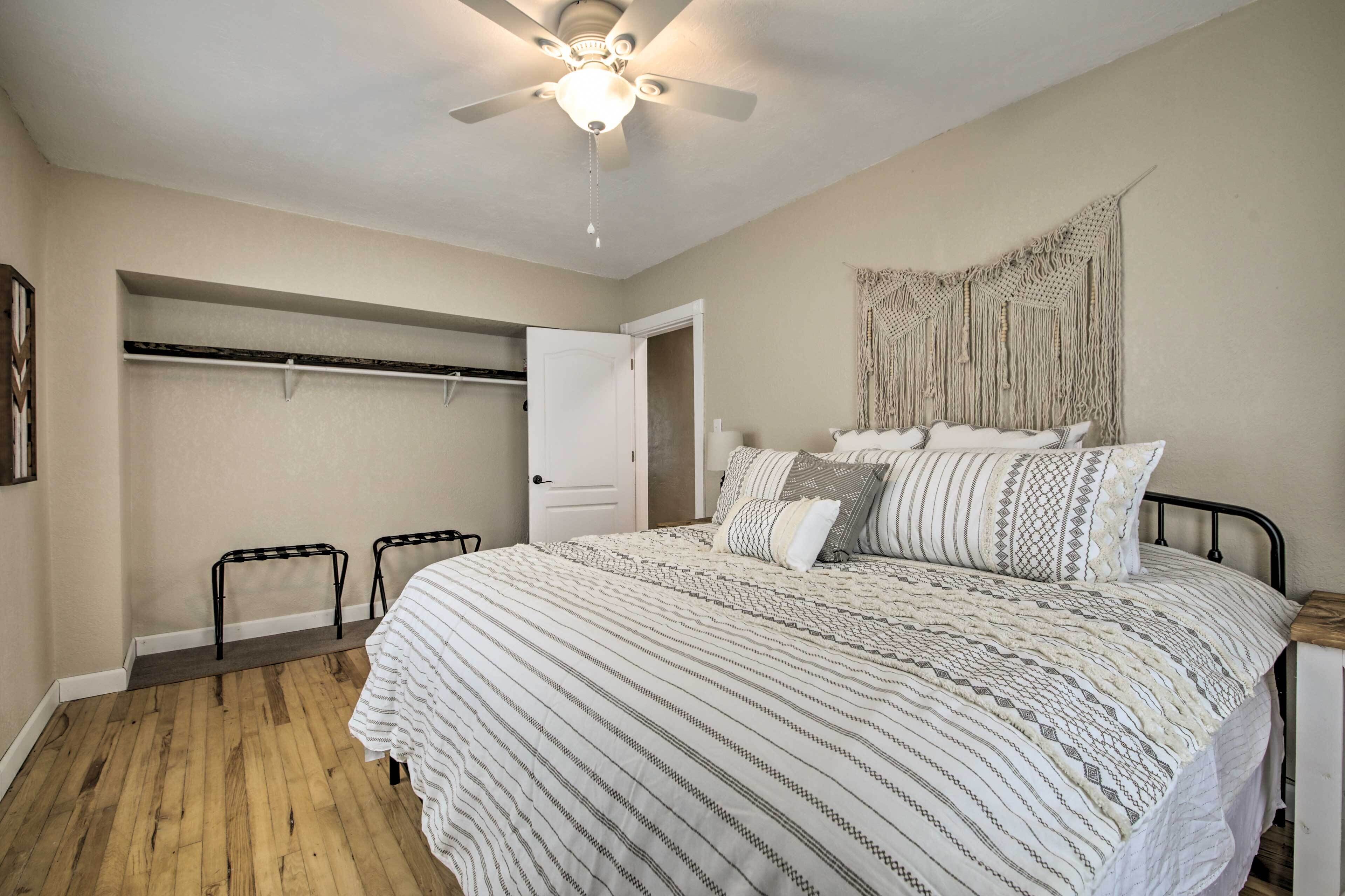 A bedroom with a bed, a ceiling fan, a wardrobe, and a door leading to another room.
