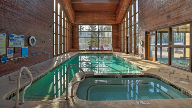 En indendørs swimmingpool med trævægge og store vinduer.
