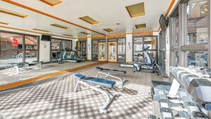 Et fitnesscenter med træningsudstyr, spejle og et mønstret tæppe.