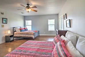 A bedroom with two beds, a ceiling fan, and two windows. - Gingerland Ranch in Del Valle: Game Room & Porch (Del Valle)