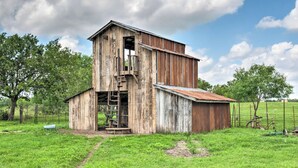 A rustic barn with a wooden exterior, a metal roof, and a ladder leading to a loft area. - Gingerland Ranch in Del Valle: Game Room & Porch (Del Valle)