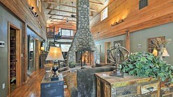Un interior espacioso con chimenea de piedra, vigas de madera y una zona de estar acogedora.