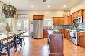 A kitchen with wooden cabinets, stainless steel appliances, a chandelier, and a dining area with a table and chairs. - Private Patio + Gazebo: Show Low Hideaway! (Show Low)