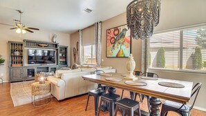 A spacious living room with a dining area, a ceiling fan, a large painting, and a view of the outdoors. - Private Patio + Gazebo: Show Low Hideaway! (Show Low)