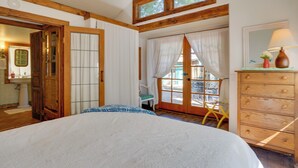 A bedroom with a bed, wooden dresser, and a window with curtains.