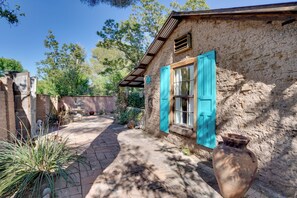 A rustic stone building with a tiled patio, a large clay pot, and a small fountain.
