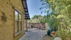 A courtyard with a stone pathway, a cactus, and a large spherical sculpture.