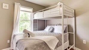 A bunk bed with a white frame, a quilted bedspread, and a neatly folded towel on the lower bunk. - Walkable Apt Near Kentucky Derby! (Louisville)