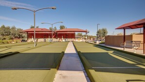 A pool table area with green felt surfaces, a central walkway, and red-roofed structures. - 55+ Gilbert Home w/ Yard, Golf Course On-site (Gilbert)