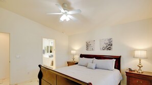 A bedroom with a wooden bed, a ceiling fan, bedside lamps, and artwork on the wall. - 55+ Gilbert Home w/ Yard, Golf Course On-site (Gilbert)