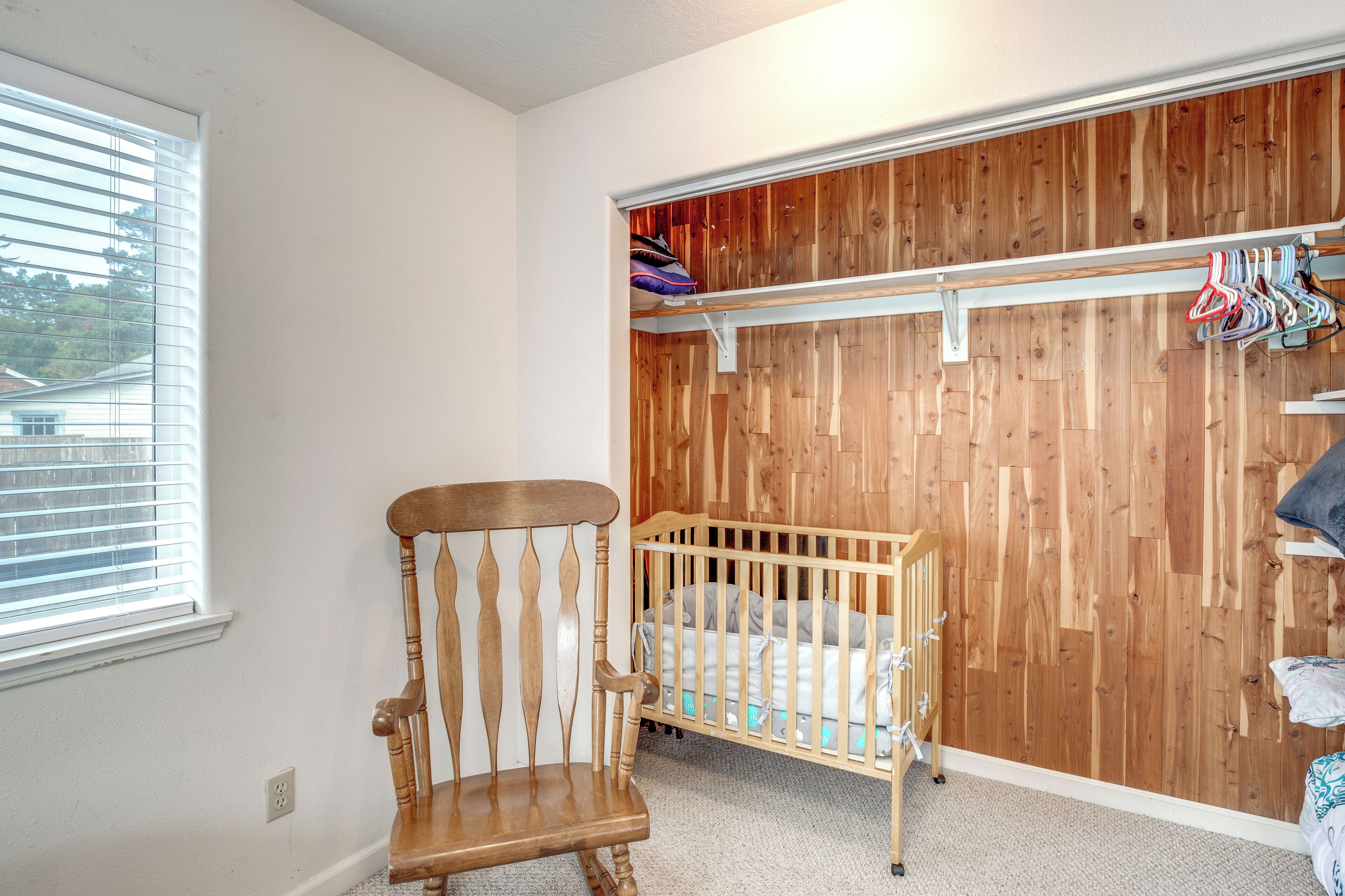 A room with a wooden crib, a wooden chair, and a wooden wardrobe with a basketball hoop.