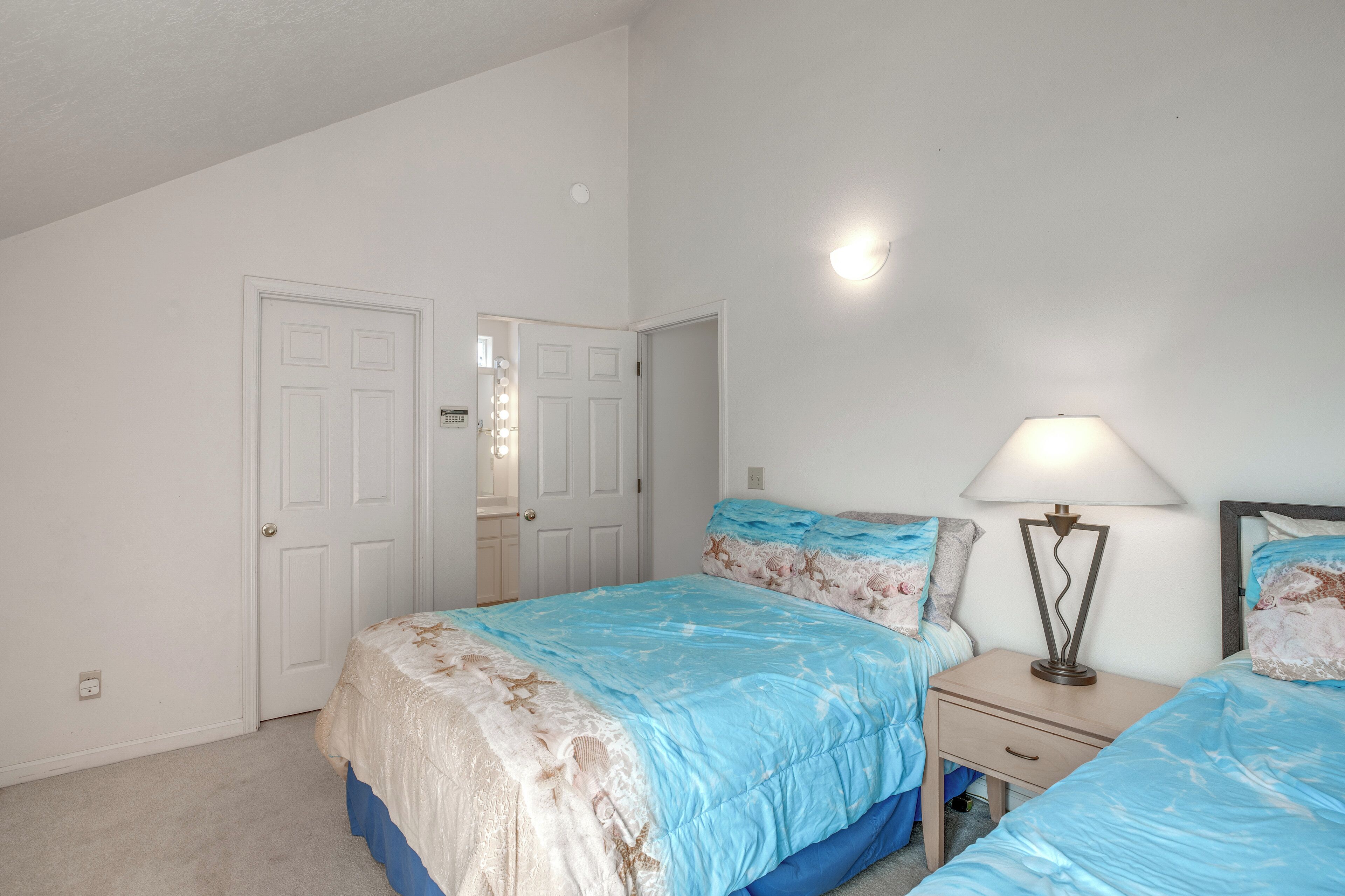 Une chambre à coucher avec un lit, une table de chevet, une lampe et une porte.