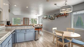 Una cocina con armarios azules, una mesa de comedor de madera y una lámpara colgante.