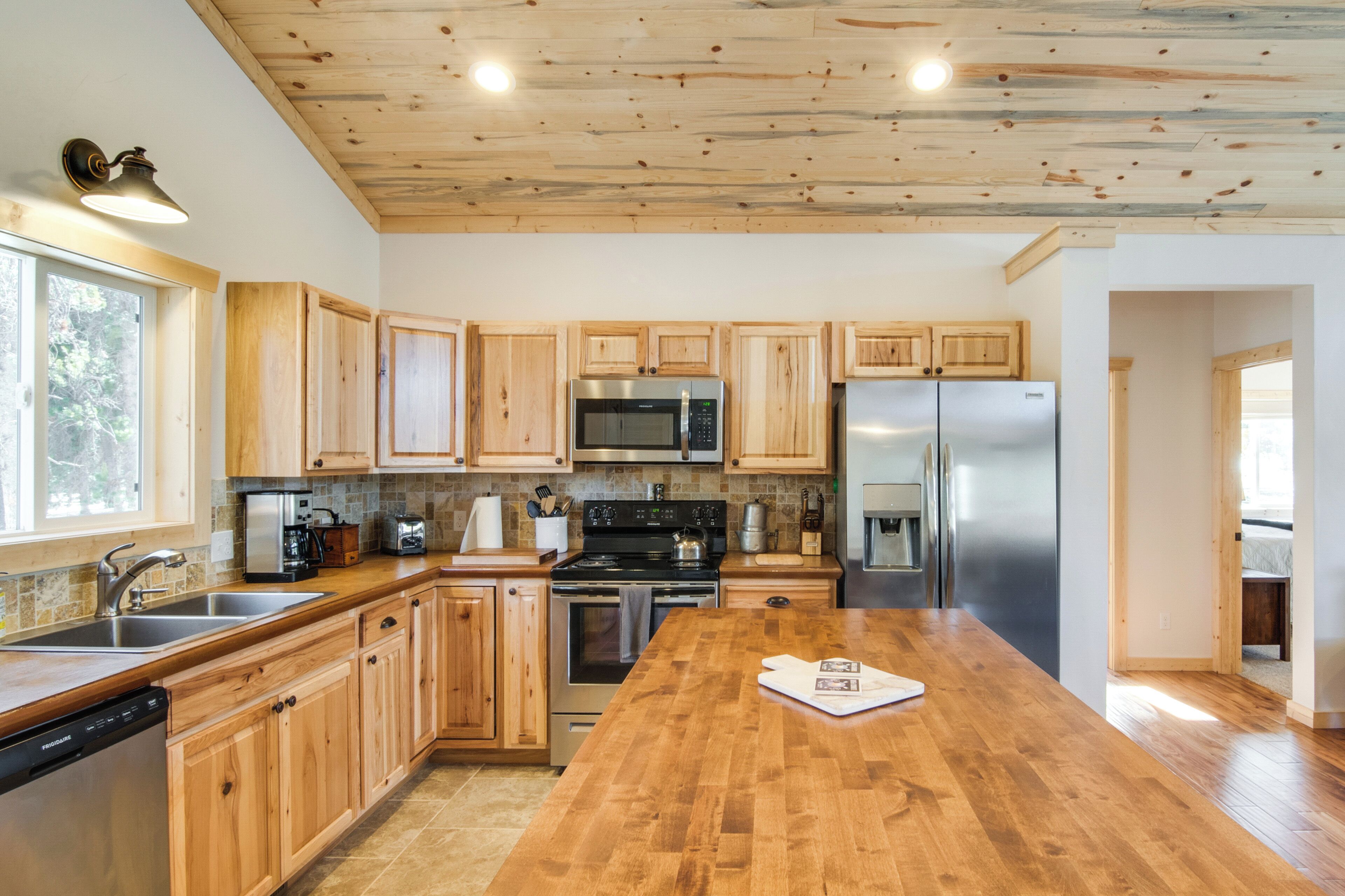 A modern kitchen with wooden cabinets, stainless steel appliances, and a wooden countertop.