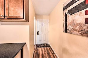 A hallway with a wooden floor, a white door, and a painting on the wall.