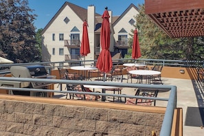A patio area with outdoor seating, a grill, and red umbrellas.