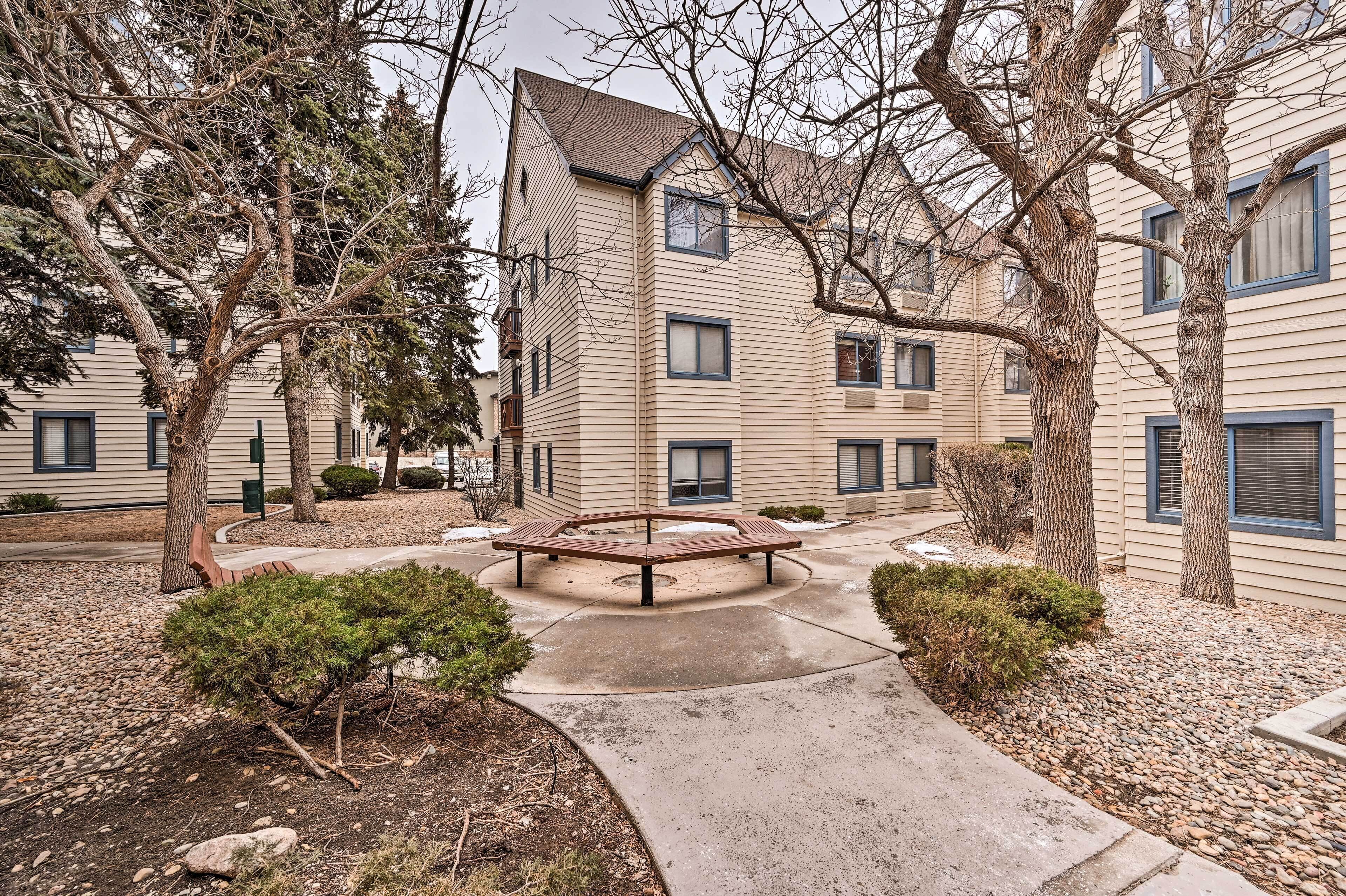 A multi-story building with a central courtyard featuring a wooden bench and small trees.