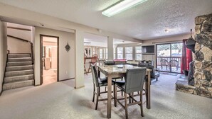 Un vaste espace de vie comprenant une table à manger, des chaises, une cheminée et une vue sur l’extérieur.