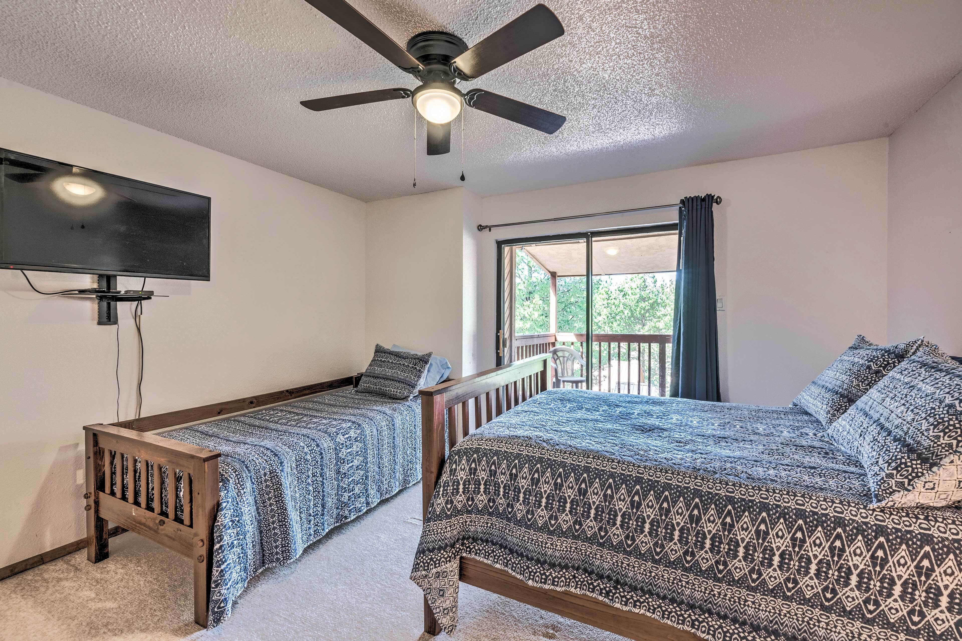 A bedroom with two single beds, a ceiling fan, a TV, and a balcony with curtains.