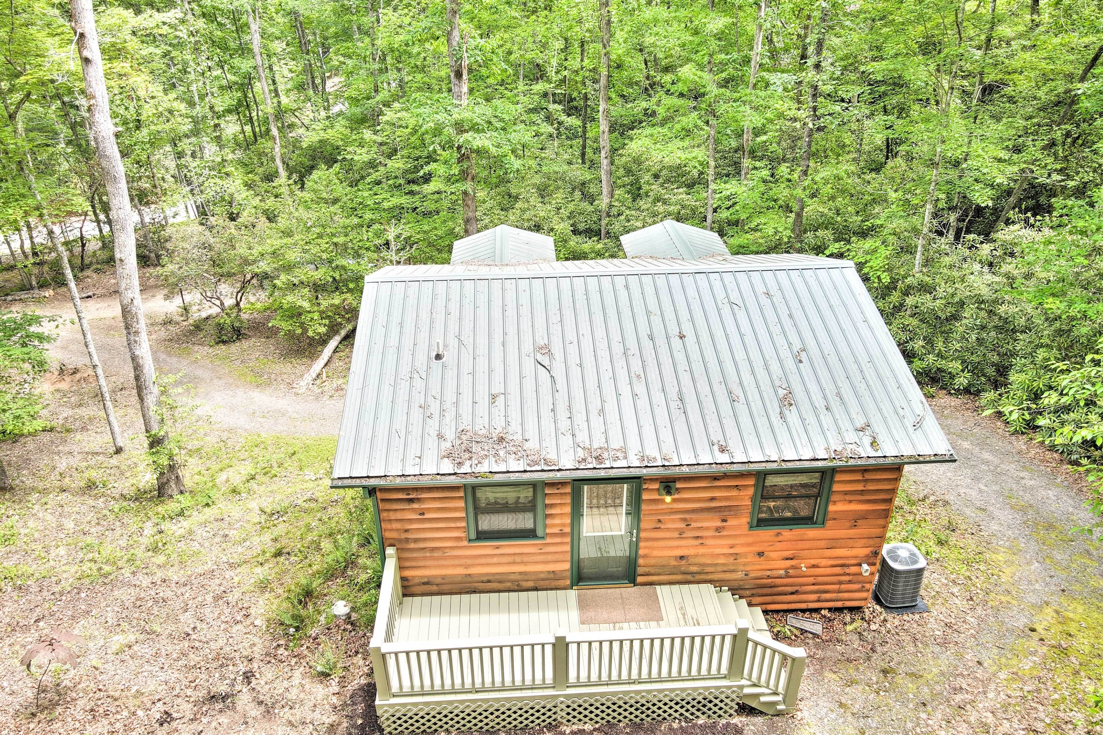 A small cabin with a metal roof, wooden walls, and a porch.