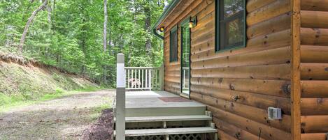 A wooden cabin with a porch and steps leading to a door.