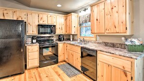 A kitchen with wooden cabinets, a refrigerator, stove, oven, microwave, and dishwasher. - Fire Pit & Forest Views: Secluded Murphy Cabin! (Murphy)