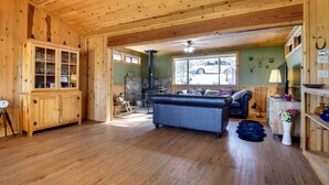 L’intérieur d’un chalet en bois, avec une cheminée, un canapé, une armoire et une horloge.