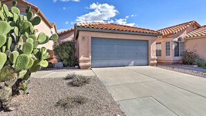 A residential house with a garage, a cactus in the foreground, and a clear blue sky. - Tucson Area House w/ Pool Access & Mountain Views! (Tucson)