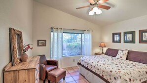 A bedroom with a bed, a desk, a chair, a ceiling fan, and a window with curtains. - Tucson Area House w/ Pool Access & Mountain Views! (Tucson)