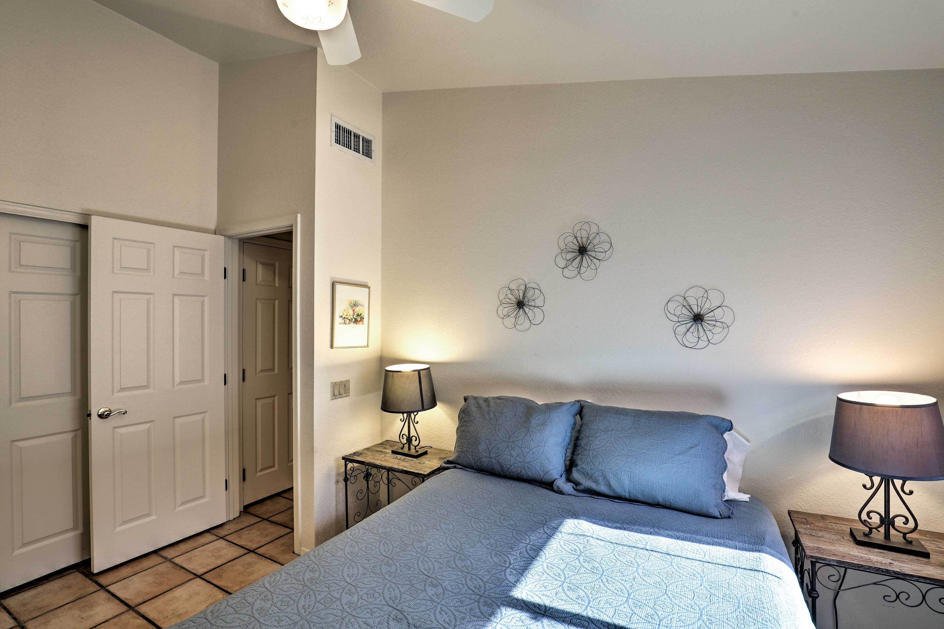 Une chambre à coucher comprenant un lit, deux tables de chevet avec des lampes, une porte et des éléments de décoration murale.
