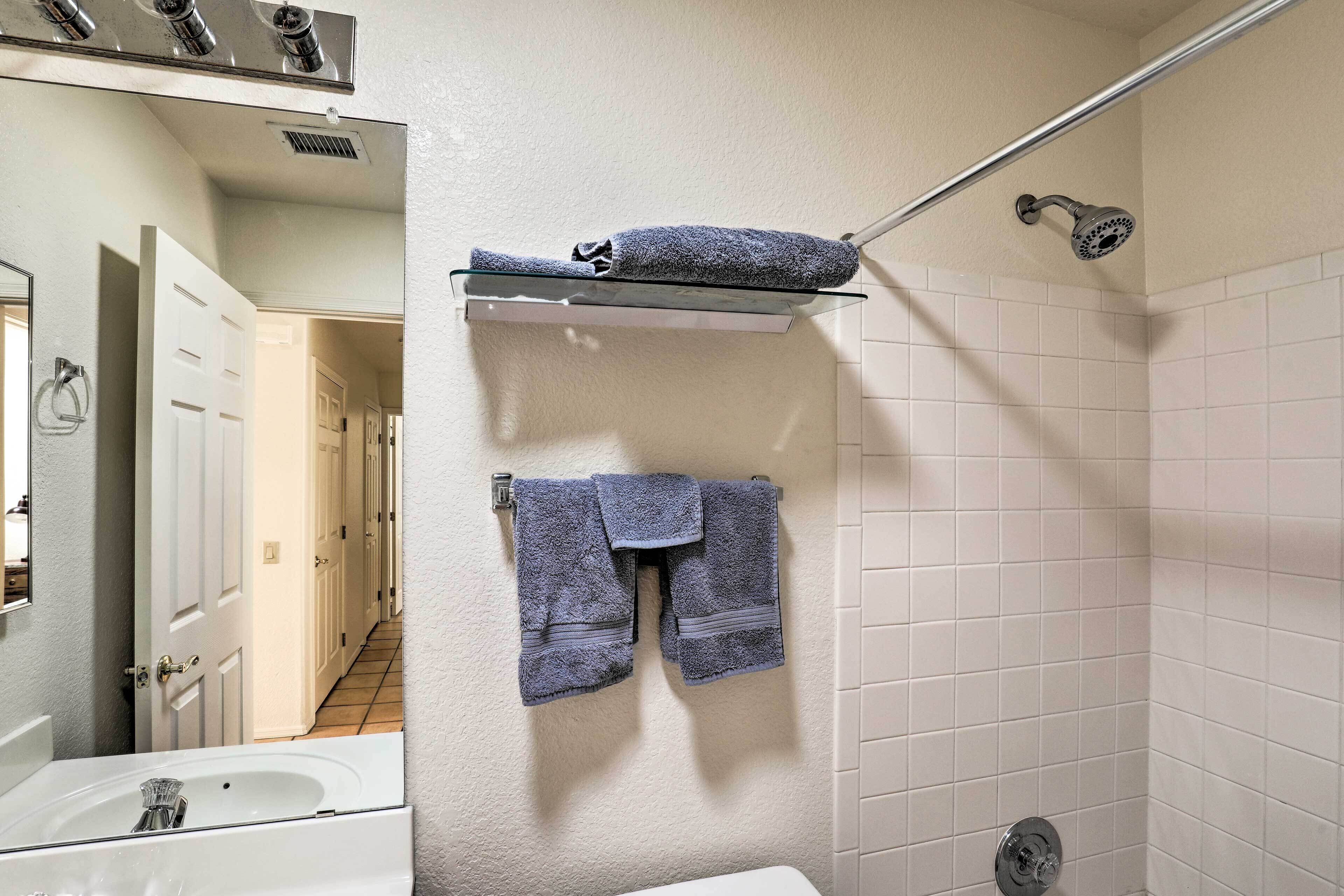 A bathroom with a white sink, a glass shower enclosure, and a towel rack with two towels.