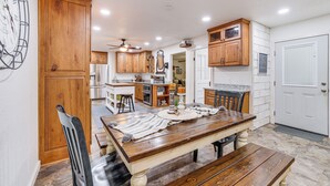 A spacious kitchen with wooden cabinets, a central island, and a dining area with a wooden table and chairs. - Views! Lake Home w/ 2 Decks, Boat Parking & Peace (Garfield)
