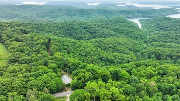 Vue aérienne d’une forêt dense, avec une route sinueuse et un petit bâtiment.
