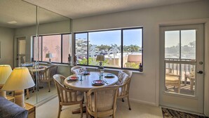 A dining area with a round table, chairs, and a view of the city through large windows. - Burnt Store Marina Condo: Boat, Swim, Golf! (Punta Gorda)
