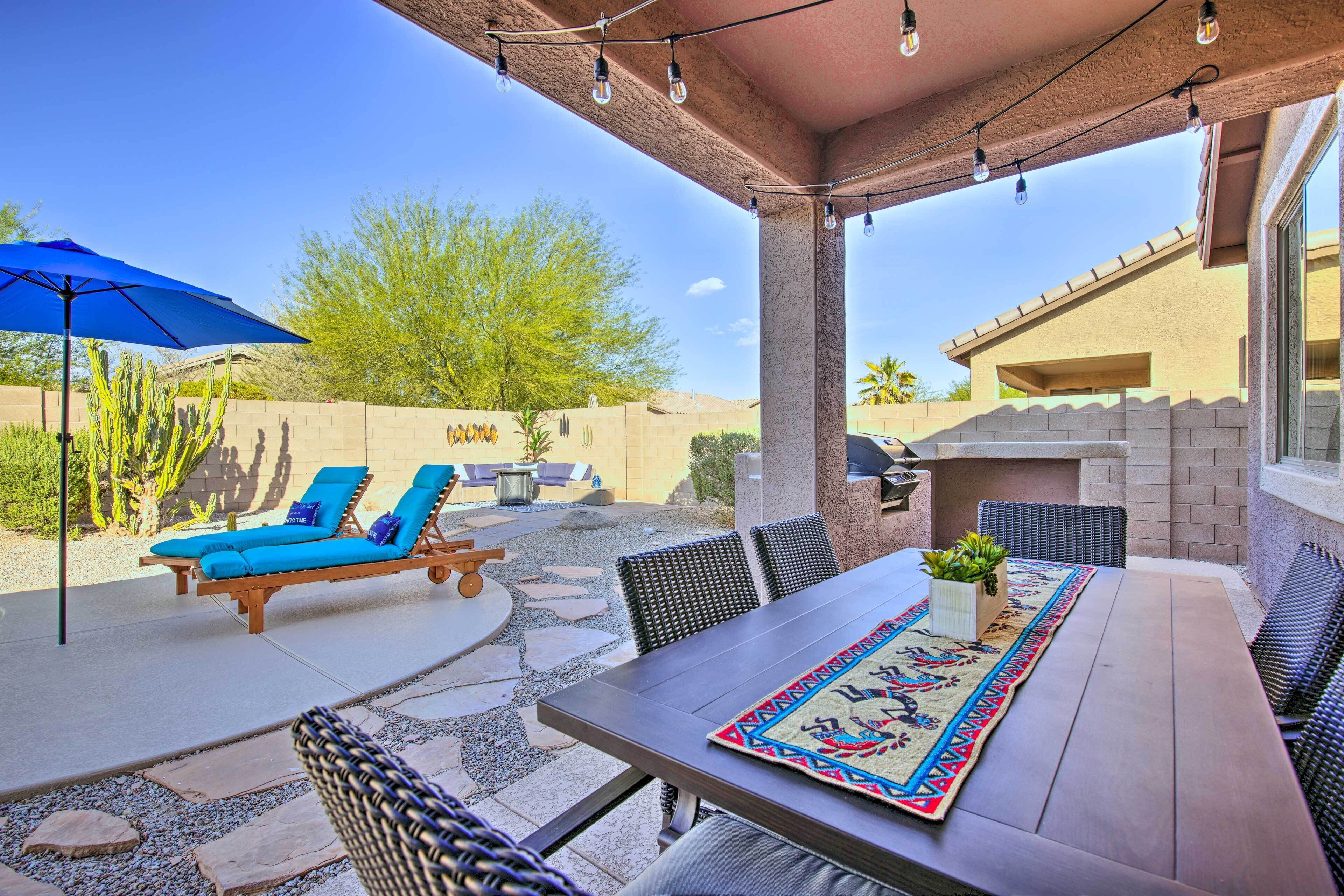An outdoor patio with a table, chairs, and a blue umbrella.