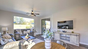A modern living room with a sofa, coffee table, and a TV mounted on the wall. - Fire Pit, Covered Patio: Stylish Goodyear Refuge (Goodyear)