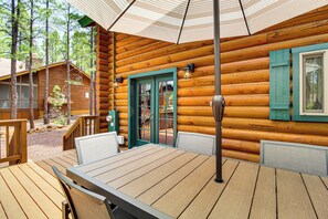 Eine Holzhütte mit einer Terrasse, einem Tisch mit Stühlen und einer Tür mit Glasfeldern.