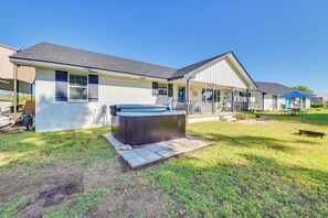 A single-story house with a hot tub in the backyard, a covered porch, and a small outdoor seating area.
