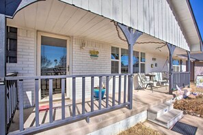A porch with a railing, a welcome sign, and a potted plant.