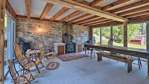 A rustic interior with exposed wooden beams, a stone wall, a fireplace, and a large dining table. - Cozy Home w/ Private Patio & Views, Hiking On-site (Belleville)