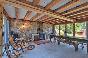 Un interior rústico con vigas de madera a la vista, pared de piedra, chimenea y una gran mesa de comedor.